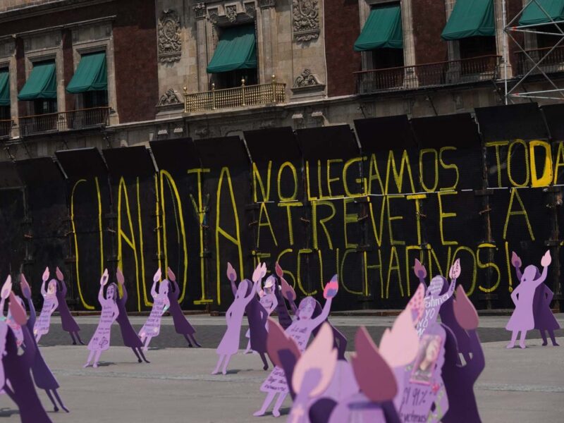 Zócalo capitalino amurallado previo al 8M. Cientos de siluetas moradas protestan contra la violencia y la impunidad en feminicidios.