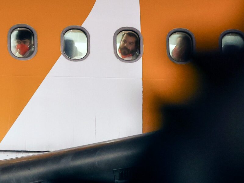Migrantes venezolanos deportados desde Estados Unidos miran por las ventanas del avión al llegar al Aeropuerto Internacional Simón Bolívar en Maiquetía, Venezuela, el 28 de marzo de 2025. (Foto por Pedro MATTEY / AFP)