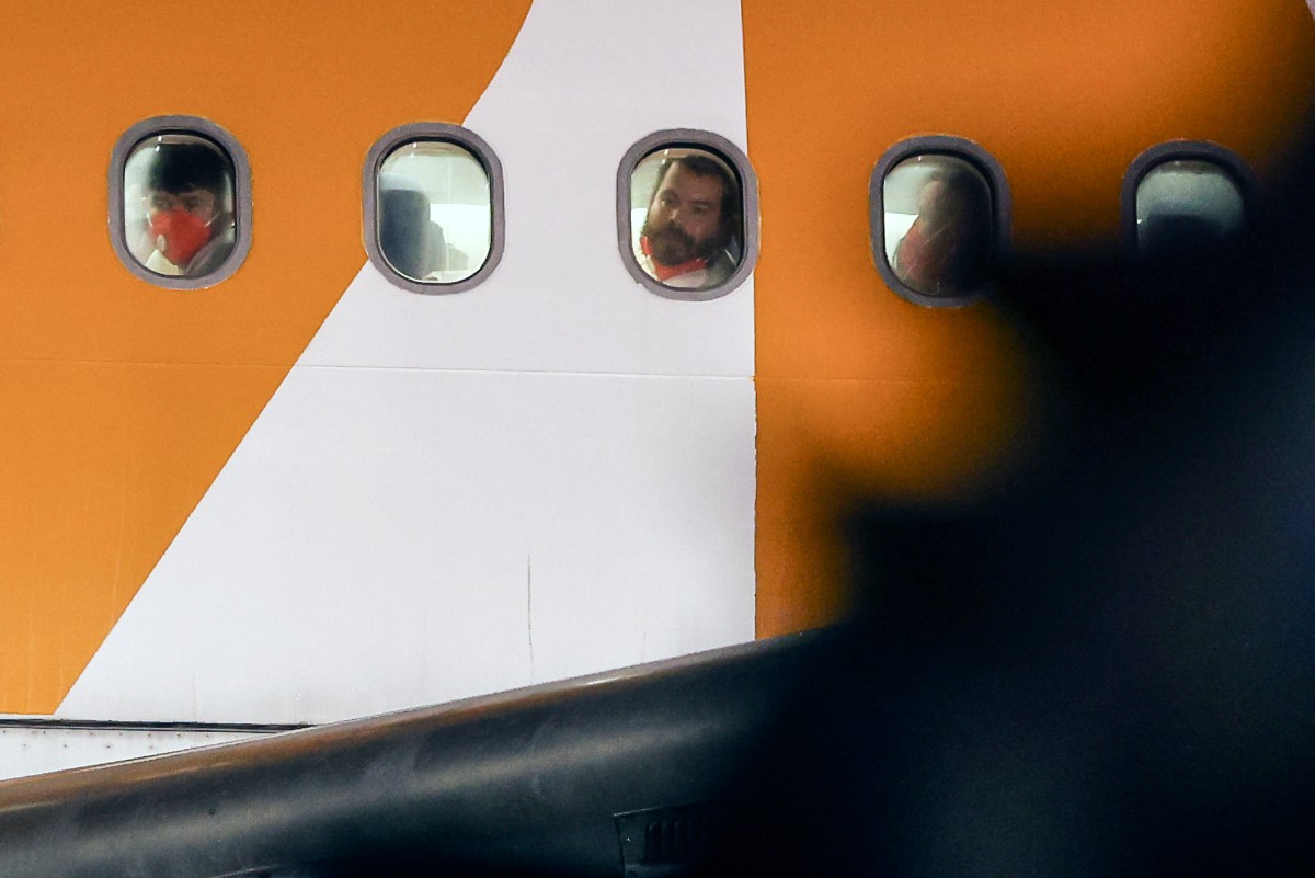 Migrantes venezolanos deportados desde Estados Unidos miran por las ventanas del avión al llegar al Aeropuerto Internacional Simón Bolívar en Maiquetía, Venezuela, el 28 de marzo de 2025. (Foto por Pedro MATTEY / AFP)