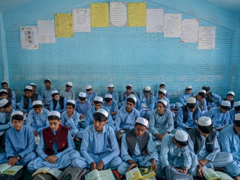 Niños afganos asisten a clases con túnicas y turbantes, como parte de los uniformes impuestos por el régimen talibán.