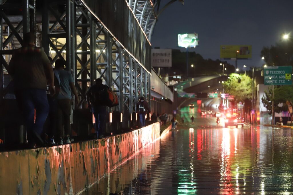Personas buscan superar la inundación de Circuito Interior pasando por una de las barsas del metro de la Línea 5. FOTO: DANIEL AUGUSTO/ CUARTOSCURO.COM