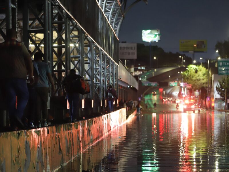 Personas buscan superar la inundación de Circuito Interior pasando por una de las barsas del metro de la Línea 5. FOTO: DANIEL AUGUSTO/ CUARTOSCURO.COM