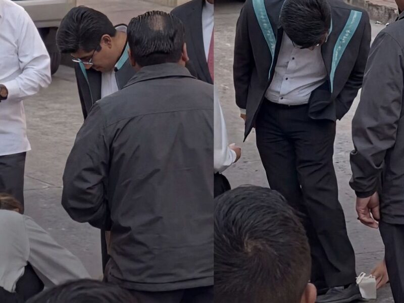 Amanda Pérez inclinada limpiando los zapatos del ministro Hugo Aguilar en Querétaro.