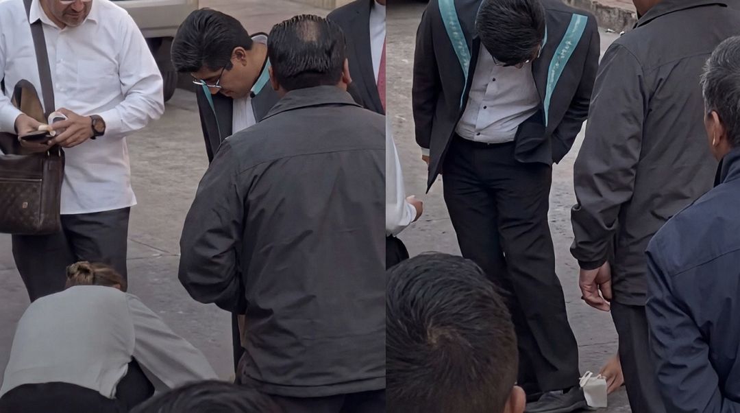 Amanda Pérez inclinada limpiando los zapatos del ministro Hugo Aguilar en Querétaro.